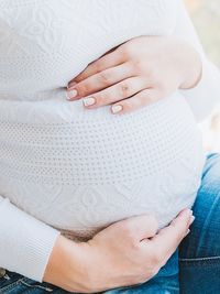 Schwangere Frau fühlt sich wohl und hält ihren Babybauch beim Geburtsvorbereitungskurs