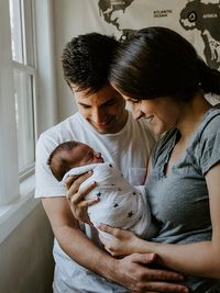 Glückliches Paar nach der Geburt mit Neugeborenem in den Armen und medizinische Versorgung von der Hebamme Uta Sommer.